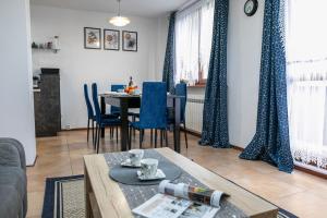 uma sala de estar com uma mesa e cadeiras azuis em Cosy Space Apartment em Tychy