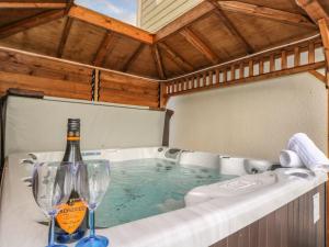 a hot tub with a bottle of wine and two glasses at Trewenna in Helston