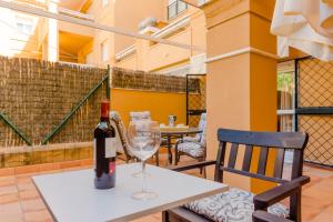 Apartamentos O2 El Puerto في إل بويرتو دي سانتا ماريا: زجاجة من النبيذ موضوعة على طاولة مع كأس من النبيذ