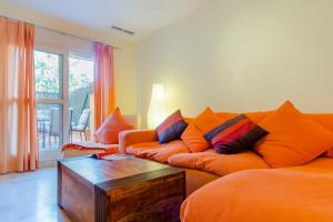 Apartamentos O2 El Puerto في إل بويرتو دي سانتا ماريا: غرفة معيشة مع أريكة برتقالية وطاولة