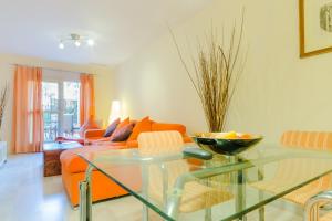 a living room with a glass table and an orange couch at Apartamentos O2 El Puerto in El Puerto de Santa María