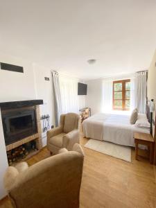 Hotel Rural Candela y Plata في Puerto de Béjar: غرفة نوم بيضاء مع سرير ومدفأة