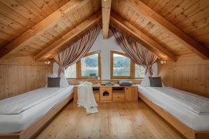 Seehotel Urban في بودينسدورف: سريرين في غرفة ذات سقف خشبي ونوافذ