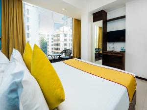a bedroom with a bed with yellow and white pillows at Hotel Aura - Near Malad Link Road in Mumbai