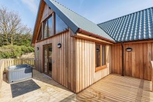 a wooden house with a large wooden deck at Kestrel Lodge 3 with Hot Tub in Newton Stewart