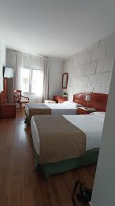 a hotel room with two beds and a chair at Hotel Boomerang in Valverde