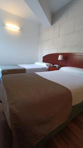 a hotel room with two beds and a lamp at Hotel Boomerang in Valverde