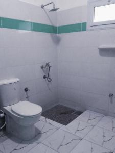 a white bathroom with a toilet and a window at Bayt Noon in Wāsiţ