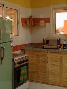 a kitchen with a green refrigerator and a microwave at Bayt Noon in Wāsiţ