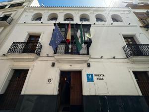 a white building with flags hanging from a balcony at Boutique Puerta Real in Seville