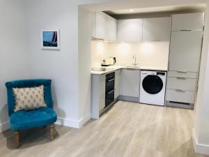 a kitchen with a washing machine and a blue chair at 5 Rockham - Luxury Apartment at Byron Woolacombe, only 4 minute walk to Woolacombe Beach! in Woolacombe