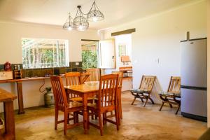 cocina con mesa, sillas y nevera en Landor Stud Farm Cottage, en Magaliesburg