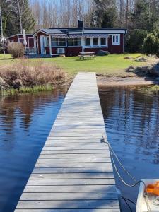 a dock with a boat in front of a house at Rinkaby Stugområde 31 in Tävelsås