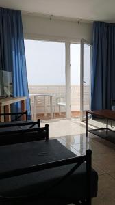 a bedroom with blue curtains and a view of a patio at Apartamentos Boomerang I in Tamaduste