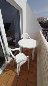 a white table and a white chair on a balcony at Apartamentos Boomerang I in Tamaduste