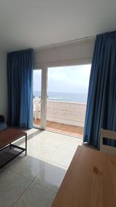 a living room with blue curtains and a view of the ocean at Apartamentos Boomerang I in Tamaduste