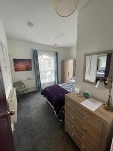 - une chambre avec un lit, une commode et un miroir dans l'établissement Victoria Villas, à Sandycroft