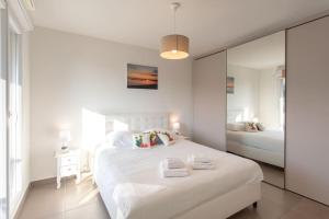 een witte slaapkamer met een groot wit bed met spiegels bij L8 Calm, panoramic Sea View withTerrace, Parking & AC in Saint-Laurent-du-Var