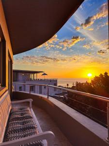 a bench on the balcony of a house with the sunset at One On Houghton in Cape Town