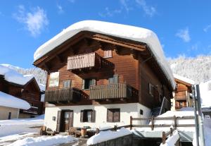 una casa di tronchi con neve sul tetto di Bait dal Molin Florin a Livigno