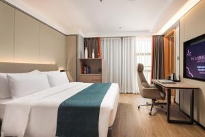 a hotel room with a bed and a desk and a computer at Zhongshan Phoenix By Funyard in Zhongshan