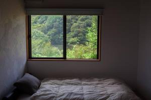 ein Schlafzimmer mit einem Bett und einem großen Fenster in der Unterkunft kaso Space kamiyama Log House 