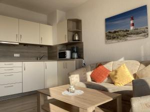 uma sala de estar com um sofá, uma mesa e um farol em Haus am Deich Wohnung 13 em Dahme