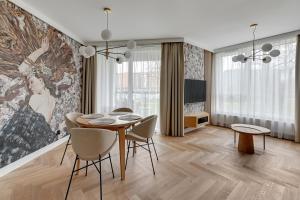 a dining room with a table and chairs and a painting at RentPlanet - Apartamenty Chlebova in Gdańsk