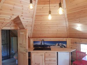 a kitchen in a log cabin with a sink and lights at Kota SHANTYHOME in Saint-Martin-dʼArc