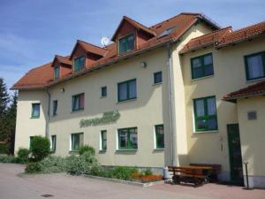 ein großes Gebäude mit einer Bank davor in der Unterkunft Pension Schwalbennest in Bösleben-Wüllersleben