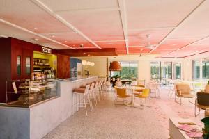 a restaurant with a bar and tables and chairs at Greet Hotel Versailles - Voisins Le Bretonneux in Voisins-le-Bretonneux