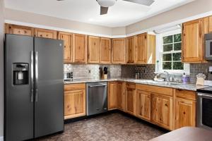 La cuisine est équipée d'armoires en bois et d'un réfrigérateur en acier inoxydable. dans l'établissement Waynesboro Home Near Wintergreen Charlottesville, à Waynesboro