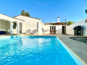 - une piscine en face d'une maison dans l'établissement Acacias belle maison avec Piscine chauffée, Spa et Sauna, à Rivedoux-Plage