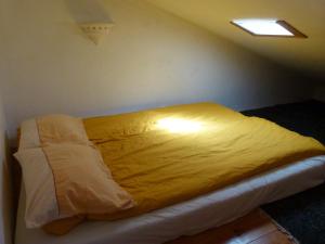 Una cama en una habitación con una manta amarilla. en Casa da Marina, en Aljezur