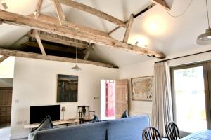 a living room with a blue couch and a tv at Gull Farm Barn in Burgh