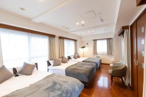 a row of four beds in a room with windows at Ocean Niponichi in Osaka