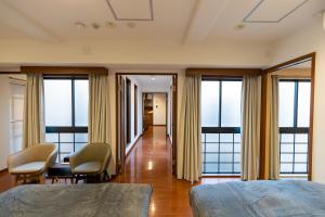 a bedroom with a bed and chairs and windows at Ocean Niponichi in Osaka