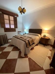 1 dormitorio con 1 cama y suelo a cuadros en Casa Cumbres, en Cumbres de San Bartolomé