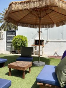 een patio met stoelen, een parasol en een grill bij על הנחל in Bet Sheʼan