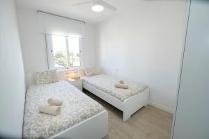 - une chambre blanche avec 2 lits et un miroir dans l'établissement La Brisa Marina, à Roda de Bará