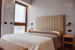 a bedroom with two beds and a clock on the wall at GuerriniBNB Civico 5 in Manerbio