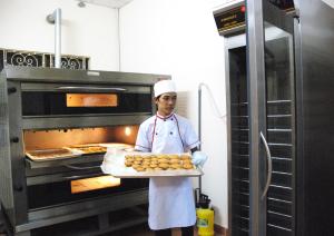 a chef holding a tray of food in an oven at Nhà Khách Làng May Mắn - Village Chance in Ho Chi Minh City