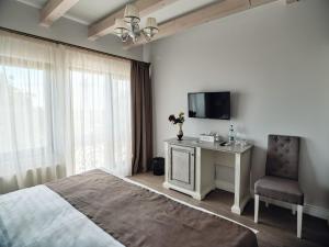 a bedroom with a bed and a tv and a chair at Domeniile Panciu Winery & Resort in Sîrbi
