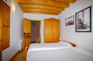 アルネディリョにあるCasa Arnedilloの白いベッドと木製の天井が備わるベッドルーム1室が備わります。