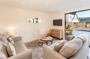 a living room with two couches and a table at 1 Challacombe - Luxury Apartment at Byron Woolacombe, only 4 minute walk to Woolacombe Beach! in Woolacombe