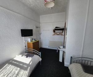 a small room with two beds and a tv at The Moorfield in Blackpool