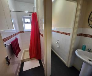 a bathroom with a red shower curtain and a sink at The Moorfield in Blackpool
