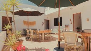 Un patio con una mesa y sillas y una sombrilla. en Hostal Esfigueral, en Playa Es Figueral