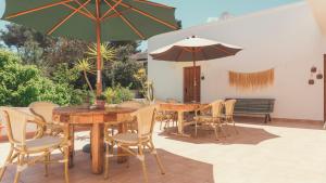 Un patio con mesas, sillas y sombrillas. en Hostal Esfigueral, en Playa Es Figueral