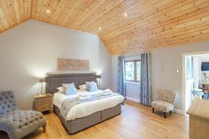 a bedroom with a large bed and a wooden ceiling at Osprey Lodge 1 with Hot Tub in Newton Stewart